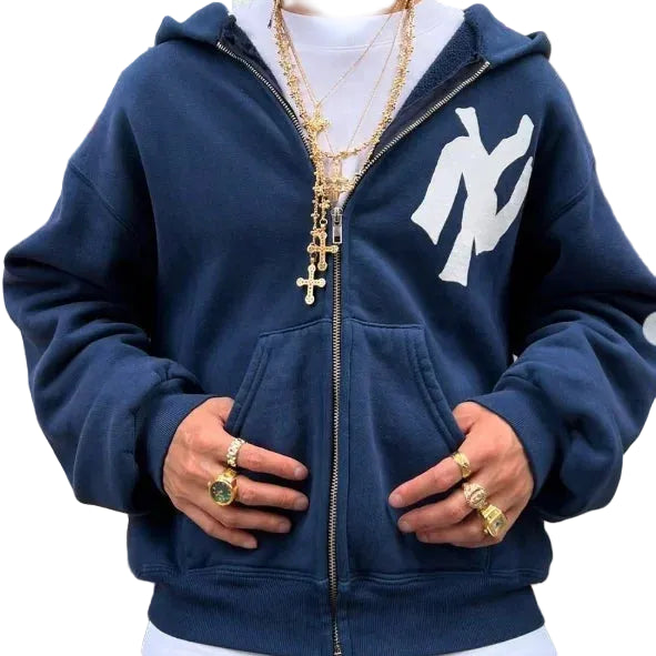 Person wearing a navy blue hoodie with a logo, standing outdoors.