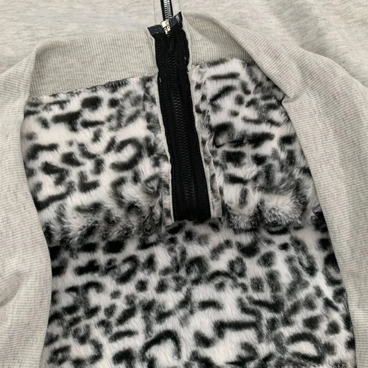 Close-up of a light gray ribbed garment with a black zipper and a plush faux-fur insert in a black-and-white leopard print.