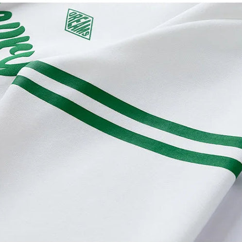 Close-up of a white shirt with green accents and brand logo.