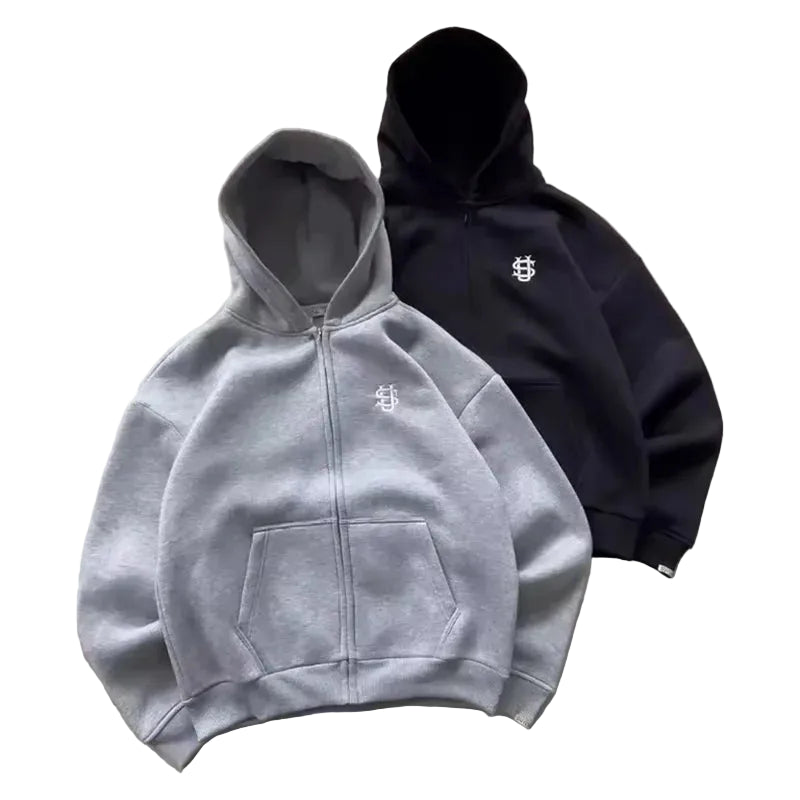 Gray and black hoodies with a logo on a concrete surface