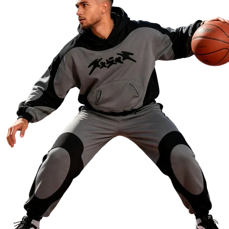 Person in gray and black outfit with 'Frogg' logo holding a basketball on an outdoor court.