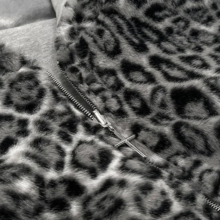 Close-up of a leopard-print faux fur garment with a silver zipper and a small cross zipper pull, shown in black and white.
