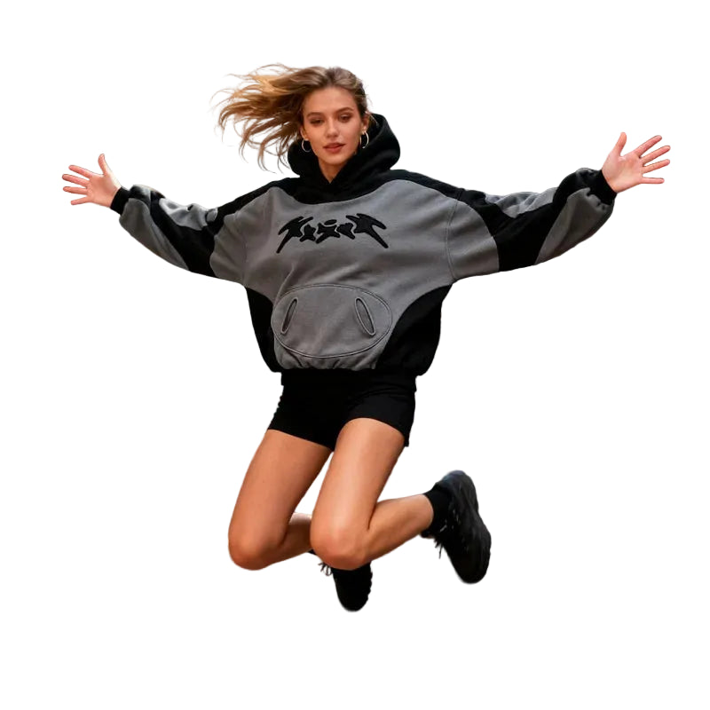 Person in a gray and black hoodie jumping in an urban street with colorful graffiti.