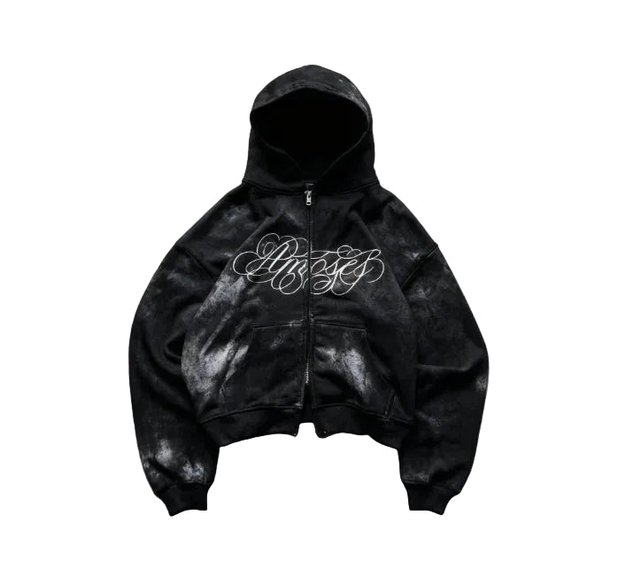 Black hoodie with white text on a textured surface with greenery