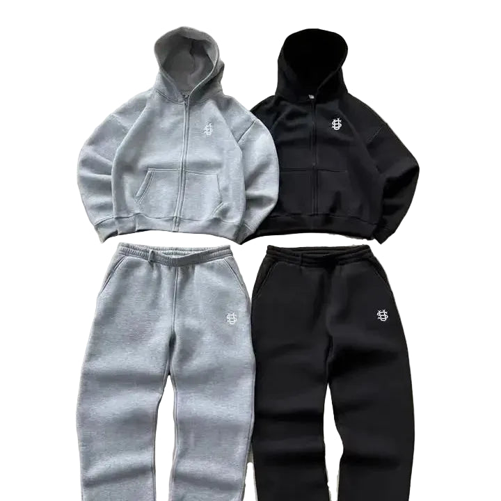 Gray and black tracksuits with brand logos on a concrete surface