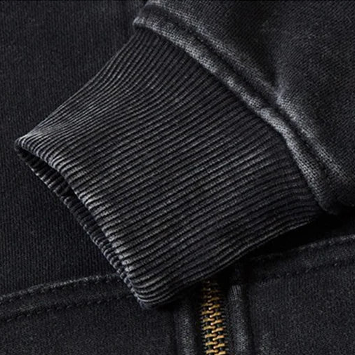 Close-up of a black jacket with a zipper, highlighting loose neckline and cuffs.