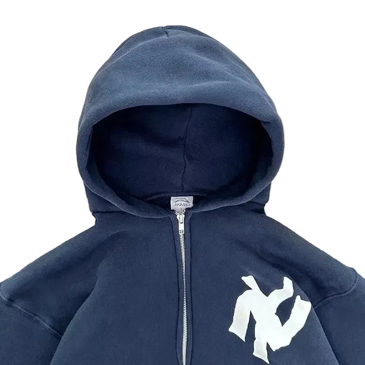 Navy blue hoodie with a white logo on a gray concrete surface