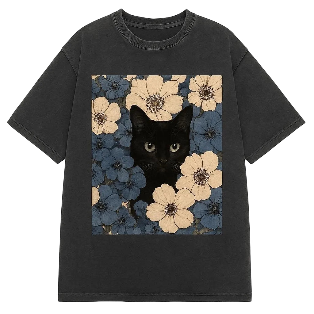 Black t-shirt with a design of a black cat peeking out from flowers on a white background